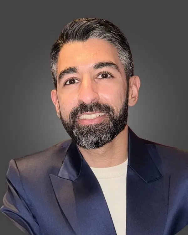 Pavan Mohal smiling, in a navy blazer